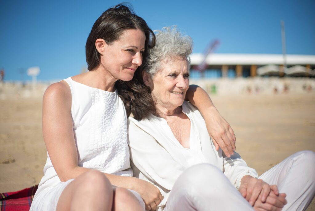 A loving mother and daughter embrace while sitting on the beach in Portugal.